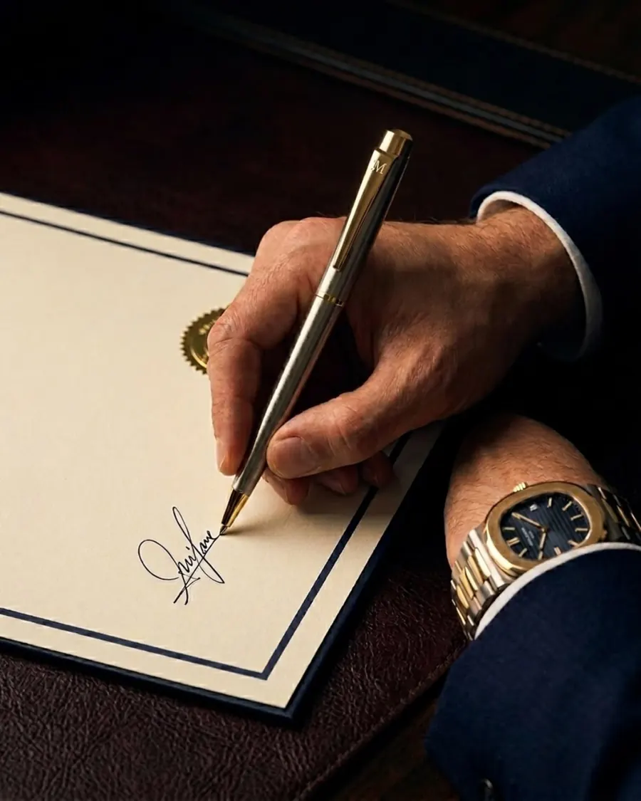 Mão com caneta dourada assinando um documento formal