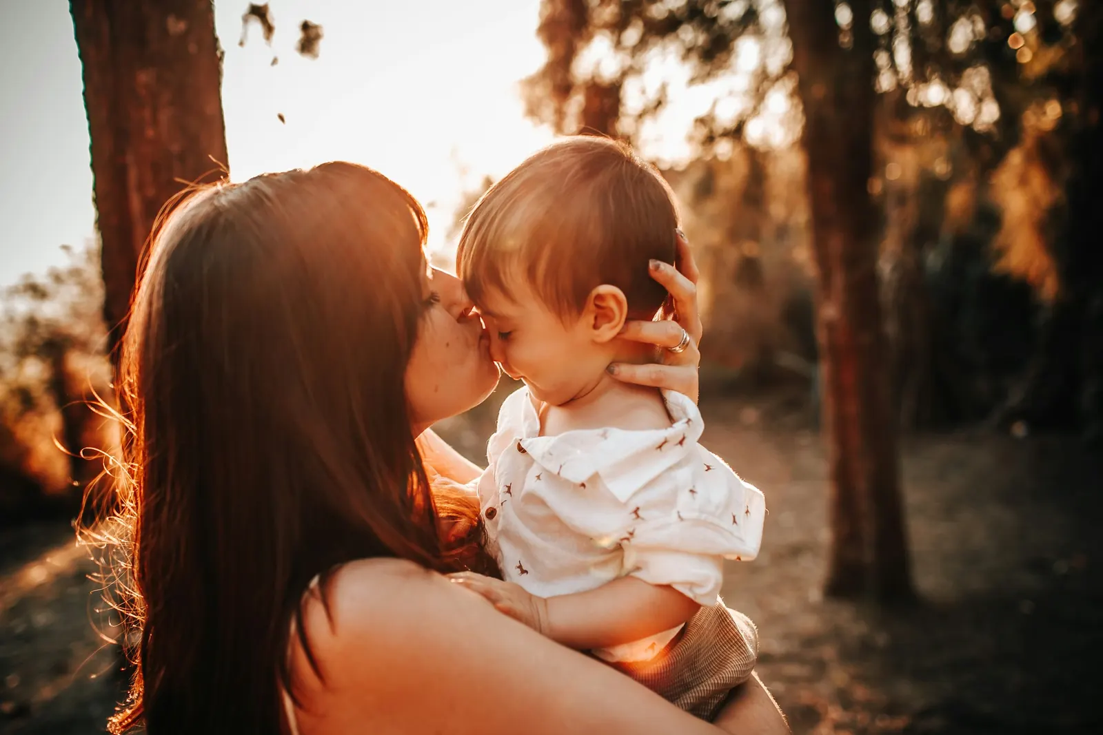 Mãe segurando o bebê sob a luz dourada do fim de tarde